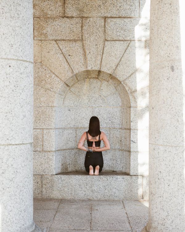Woman in a calm, focused yoga posture against a soft, serene background.